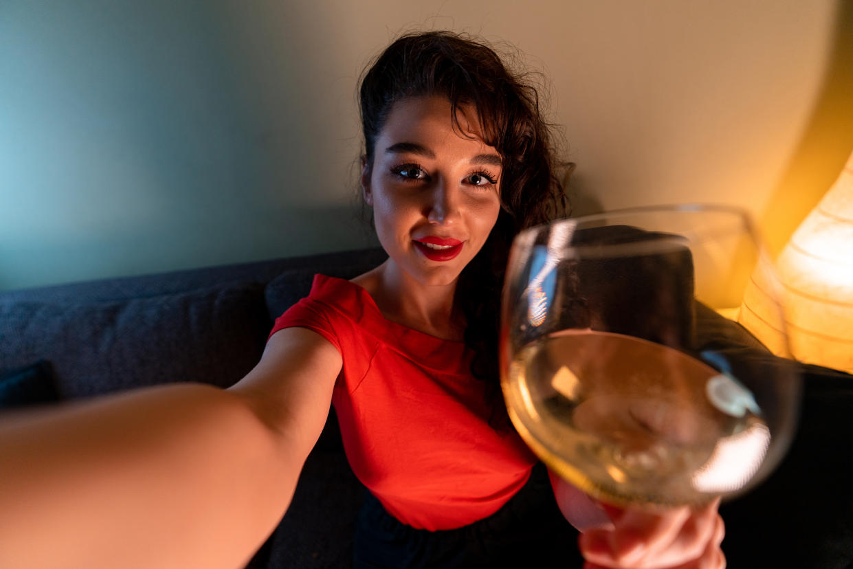 Woman Holding Glass of Wine, Smiling and Making Selfie For Friends or Relatives. Online Cheers, Meeting in Social Distancing And Isolation. Communication in Time of Quarantine.