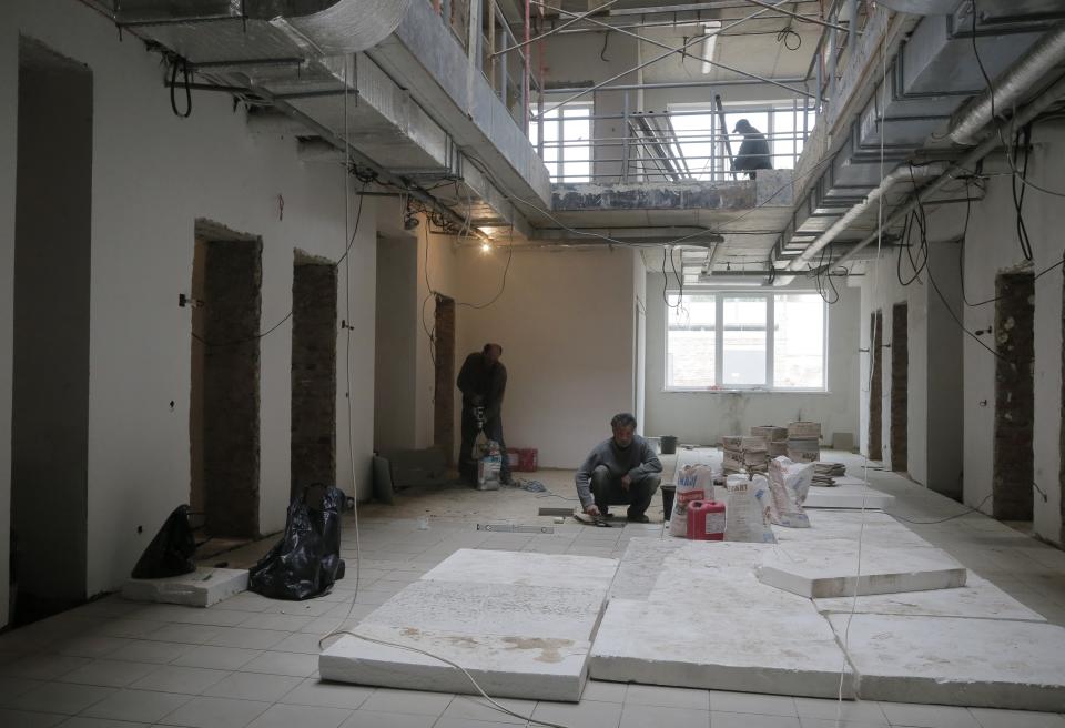 In this photo taken Tuesday, April 29, 2014, workers pave the flour with tiles in a detention center for illegal migrants under construction in Zhdanivka, near Donetsk, Ukraine, Tuesday, April 29, 2014. Moscow calls the detention center under construction near the Russian border a “fascist concentration camp.” Inside the barbed-wire fences, the reality is less ominous: It’s an EU-funded project to hold asylum seekers and illegal immigrants, similar to countless detention centers across Europe. (AP Photo/Efrem Lukatsky)