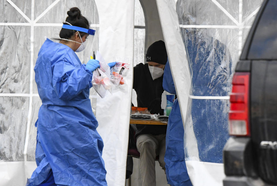 A nurse walks COVID-19 tests back to the tent at the free COVID-19 testing site on Monday, Nov. 23, 2020 in Glenwood Springs, Colo. (Chelsea Self/Glenwood Springs Post Independent via AP)