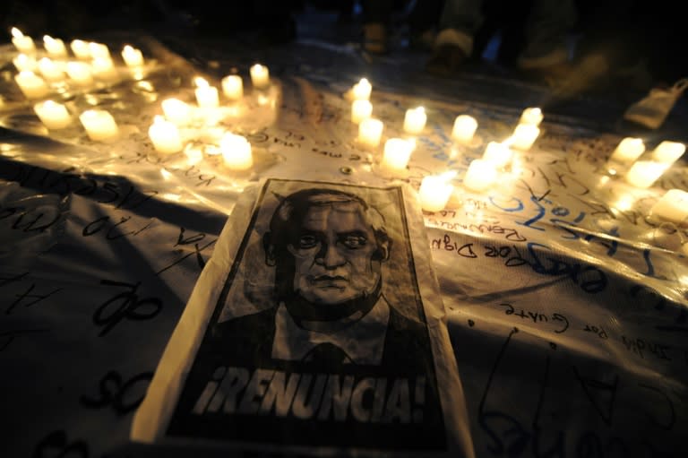 A poster depicting Guatemalan President Otto Perez reading "Resign!" lies next to candles during a demonstration in Guatemala City on August 27, 2015