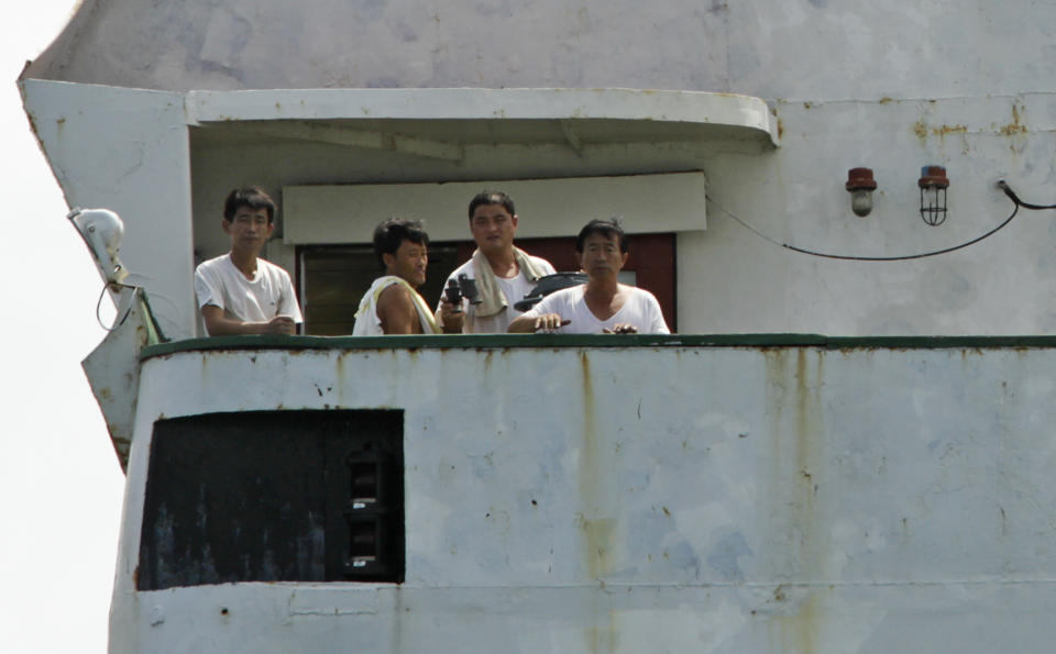 North Korean sailors look out from the deck of their cargo ship Chong Chon Gang in Sherman Bay near Colon City, Panama, Wednesday, Feb. 12, 2014. Panama Canal officials say the North Korean ship seized as it was smuggling weapons is free to leave because the owner has paid a fine. Three of the vessel's operators still face charges, while 32 crew members are free to return to North Korea. (AP Photo/Arnulfo Franco)