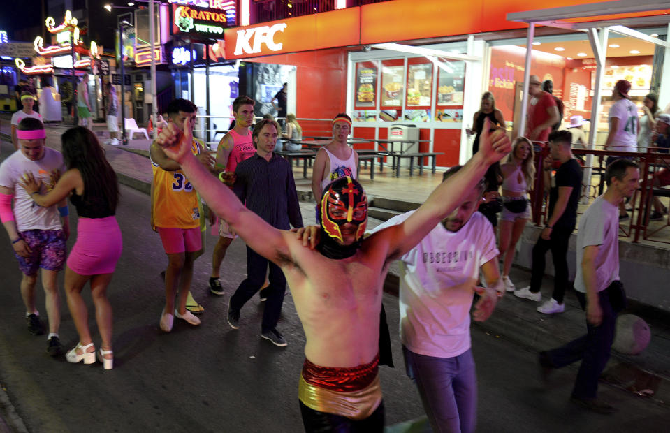 FILE - In this June 10, 2015 file photo, tourists walk on the street at in Magaluf, Calvia on the Spanish Balearic island of Mallorca, Spain. Authorities in Spain´s tourist-magnet Balearic Islands are clamping down on binge-drinking tourism in three hot-spots. The regional government has passed a law prohibiting the organization and promotion of pub crawls and publicity promoting the consumption of alcohol by means of ‘open bars’ and ‘happy hours'. (AP Photo/Joan Llado, File)