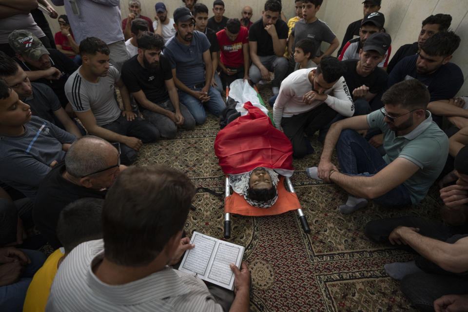 Mourners take the last look at the body of Yahia Edwan, 27 at a mosque during his funeral at the West Bank village of Azzoun, near Qalqiliya, Saturday, April 30, 2022. Israeli troops shot and killed Edwan early Saturday, the Palestinian Health Ministry said. The Israeli army said it had opened fire after a group of suspects threw firebombs toward the soldiers. (AP Photo/Nasser Nasser)