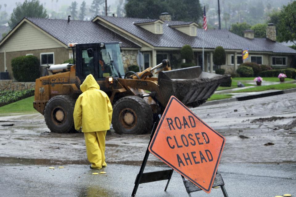 Rain falls as workers try to contain mud and water flowing from an area damaged last month by a wildfire in Glendora, California