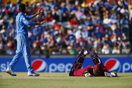 West Indies captain Jason Holder (R) lays on the pitch after getting home safely following a run out attempt alongside India's Ravindra Jadeja (L) during their Cricket World Cup match in Perth, March 6, 2015. REUTERS/David Gray