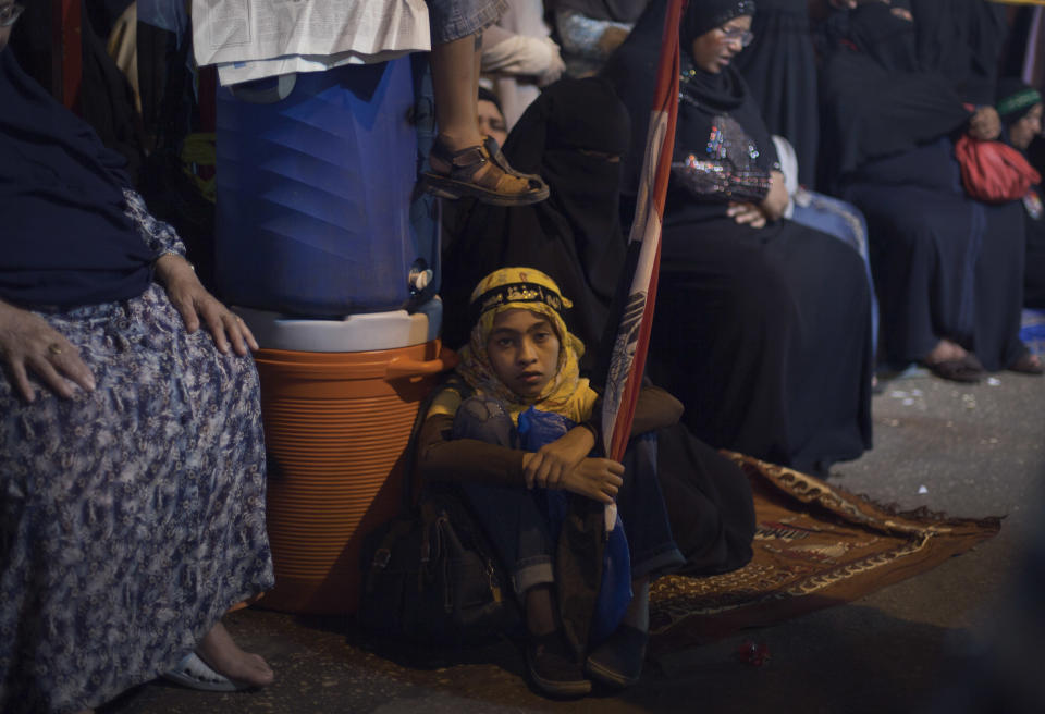 An Egyptian girl sits on the ground holding a national flag as she attends a protest with supporters of Egypt's ousted President Mohammed Morsi outside Rabaah al-Adawiya mosque, where protesters have installed a camp and hold daily rallies at Nasr City in Cairo, Egypt, Thursday, Aug. 1, 2013. (AP Photo/Khalil Hamra)