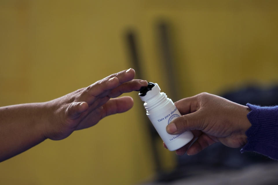 A voter has her finger stained with electoral ink after voting during general elections in Sumpango, Guatemala, Sunday, March 25, 2023. (AP Photo/Moises Castillo)