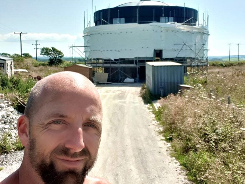 Hunt posing with the water tank home. The exterior of the tank is covered by a tarp.