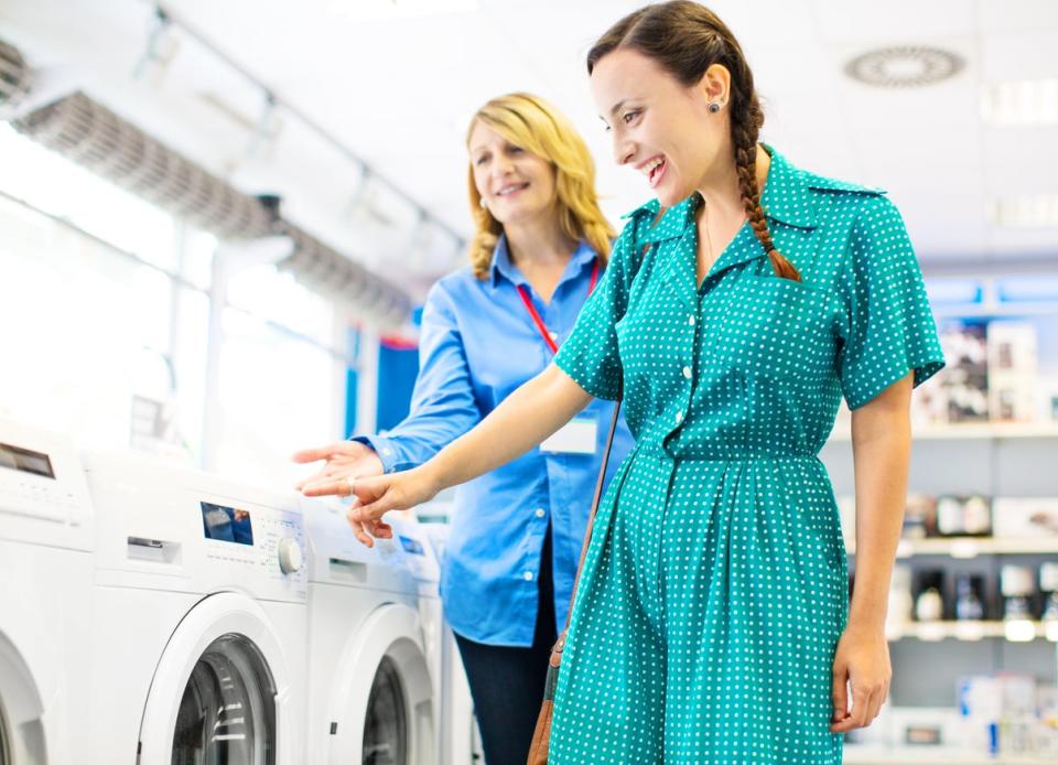 Two women shopping for washing machines at an appliance store.