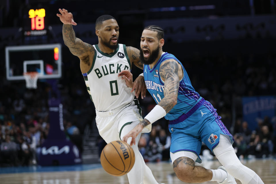 Charlotte Hornets forward Cody Martin, right, drives into Milwaukee Bucks guard Damian Lillard, left, during the first half of an NBA basketball game in Charlotte, N.C., Thursday, Feb. 29, 2024. (AP Photo/Nell Redmond)