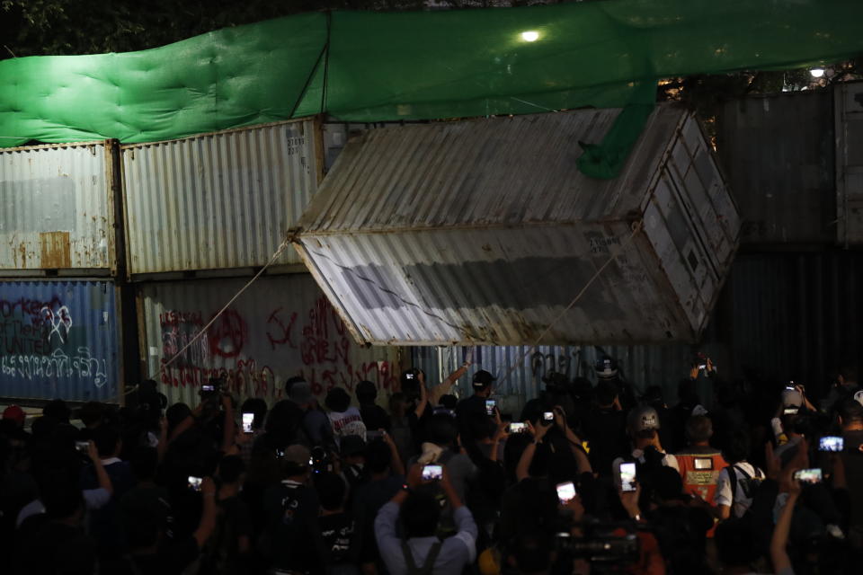Protesters pull down a shipping container used as a barricade in front of the Grand Palace Saturday, March 20, 2021, in Bangkok, Thailand. Thailand's student-led pro-democracy movement is holding a rally in the Thai capital, seeking to press demands that include freedom for their leaders, who are being held without bail on charges of defaming the monarchy. (AP Photo/Sakchai Lalit)