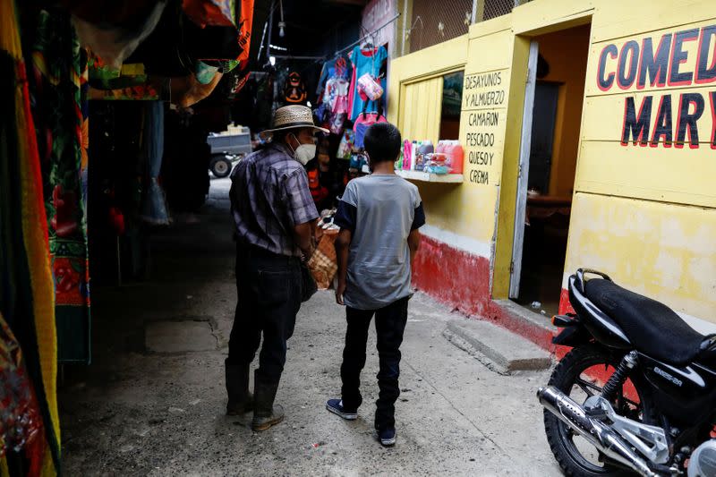 Juan habla con Gustavo, su hijo discapacitado de 12 años, quien fue expulsado por las autoridades estadounidenses a Guatemala bajo una orden de salud de emergencia, mientras llegaba a un mercado después de reunirse en Petén, Guatemala