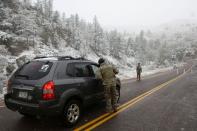 <p>Les membres de la Garde nationale du Colorado surveillent un barrage routier menant à l'incendie de Cameron Peak alors que la neige tombe un jour après que la région a subi des records de chaleur.</p>