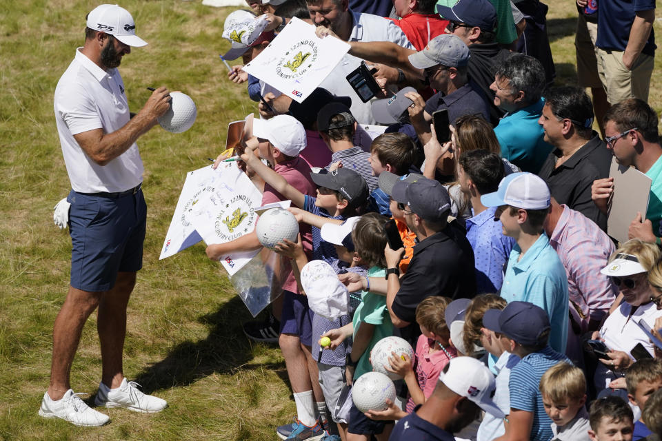 Dustin Johnson signs autographs after a practice round for the U.S. Open golf tournament at The Country Club, Wednesday, June 15, 2022, in Brookline, Mass. (AP Photo/Charles Krupa)
