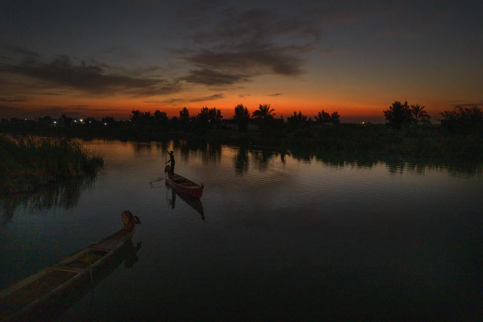 The sun sets as an Iraqi fishermen heads out on his boat in the Chibayish marshes of southern Iraq, in Dhi Qar, Iraq, Saturday, Nov. 19, 2022. (AP Photo Anmar Khalil)