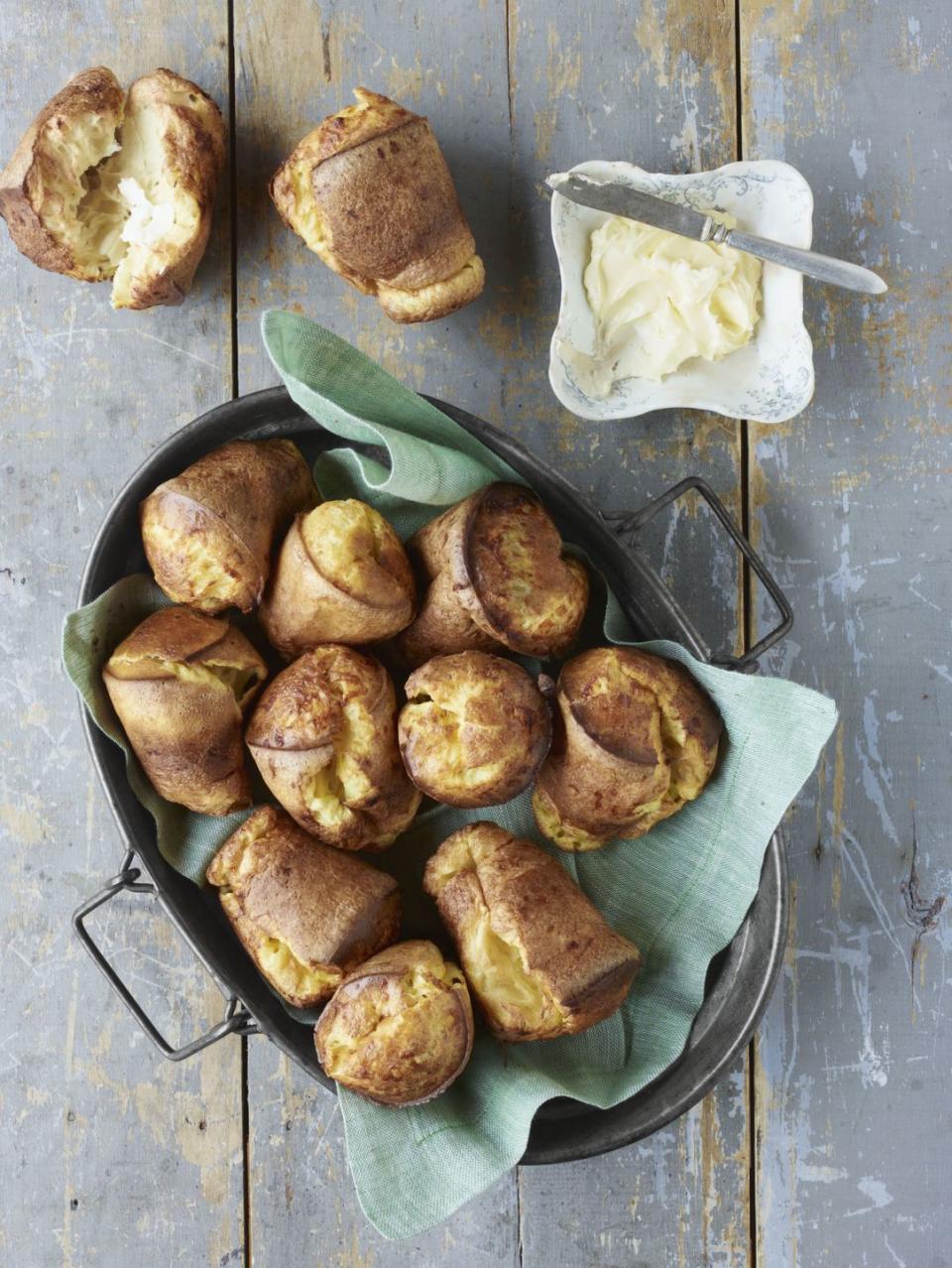 cheddar popovers in a metal serving basket lined with a light teal colored linen