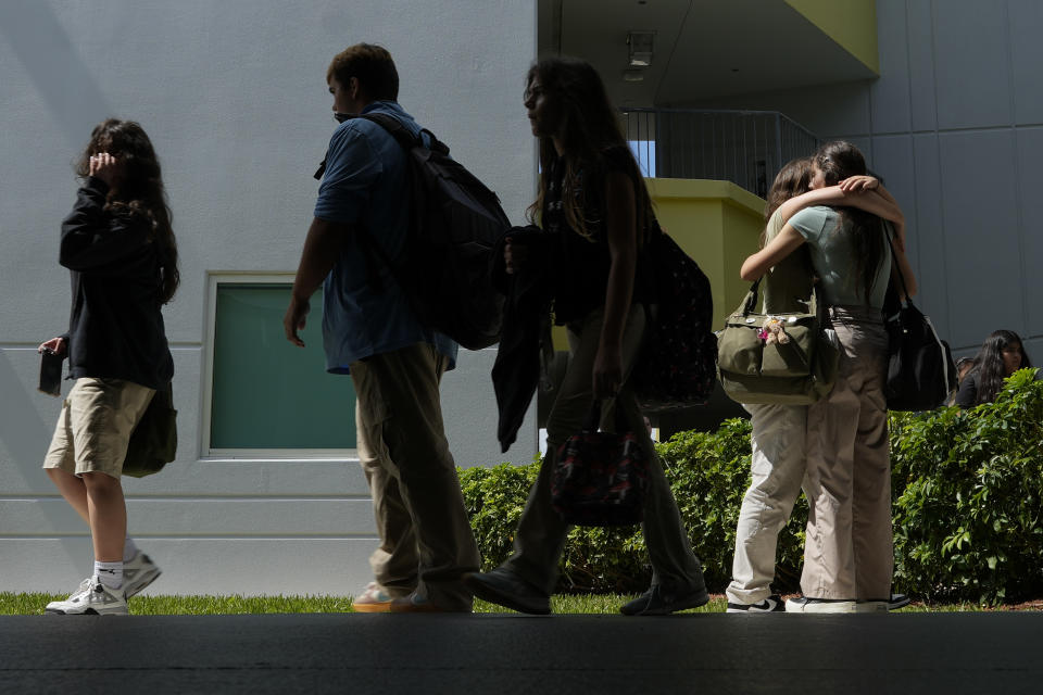 A pair of Miami Arts Studio students hug as others walk between classes, on World Mental Health Day, Tuesday, Oct. 10, 2023, at the public 6th-12th grade magnet school, in Miami. (AP Photo/Rebecca Blackwell)