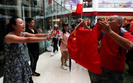 An anti-government protester gestures as she chants against a pro-government supporter holding a China flag at Olympian City 2 shopping mall in Hong Kong