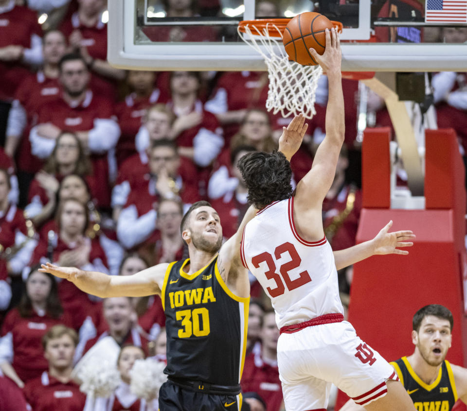 Iowa guard Connor McCaffery (30) attempts to block a shot by Indiana guard Trey Galloway (32) during the first half of an NCAA college basketball game Tuesday, Feb. 28, 2023, in Bloomington, Ind. (AP Photo/Doug McSchooler)