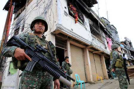 Government soldiers stand guard in front of damaged building and houses in Sultan Omar Dianalan boulevard at Mapandi district in Marawi city, southern Philippines September 13, 2017. REUTERS/Romeo Ranoco