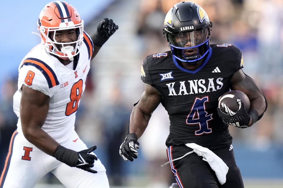 Kansas running back Devin Neal (4) is chased by Illinois linebacker Tarique Barnes (8) as he runs the ball during the first half of an NCAA college football game Friday, Sept. 8, 2023, in Lawrence, Kan. (AP Photo/Charlie Riedel)