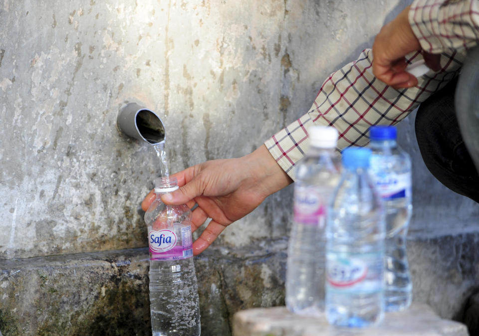 A man fills a bottle with drinkable water from a source in Sidi Bou Said, north of Tunis, Wednesday, April 12, 2023. Tunisians are on the frontlines of a battle against an increasingly severe drought, now in its fifth year in the North African country, with the government issuing a sudden order to its population to ration their water usage for six months — or risk fines or jail. (AP Photo/Hassene Dridi)