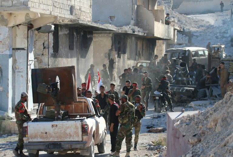 Syrian government forces gather amidst destruction in the largely deserted Palestinian refugee camp of Handarat, north of Aleppo