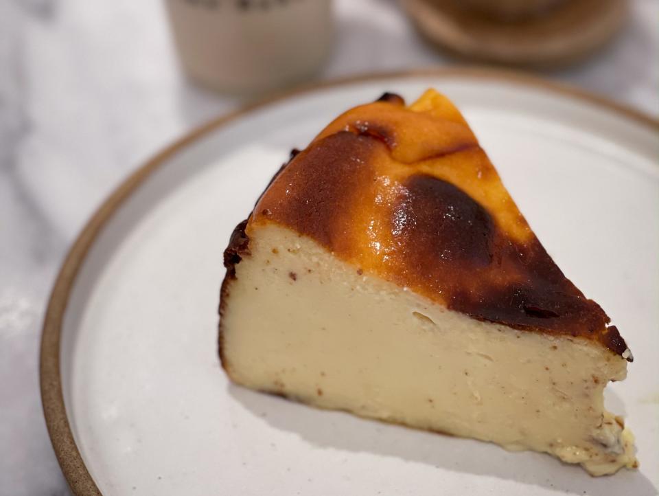 plate of cheesecake sitting on table in front of cups of coffee at Home Bakery in Dubai