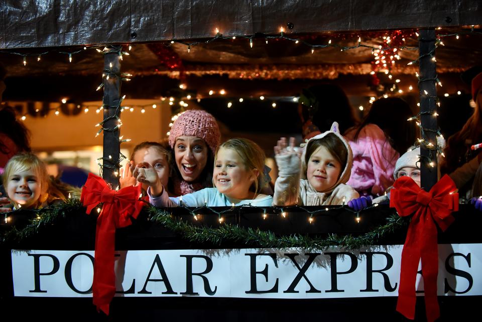 People on the Polar Express float wave to the crowd during the 'Home for the Holidays' parade in Westwood on Saturday December 1, 2018.  