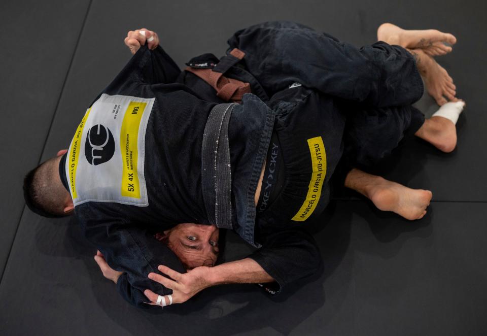 Fabio Lima, owner of 313 Brazilian Jiu Jitsu, demonstrates a move for his student Zach Mabey, a brown belt in Brazilian jujitsu (BJJ), during a class inside his gym in Detroit on Wednesday, Aug. 16, 2023. According to Lima, he was training with an injured shoulder and a fractured hip, two injuries he suffered after crossing the street near his gym and a driver ran through a stop sign, running him over.