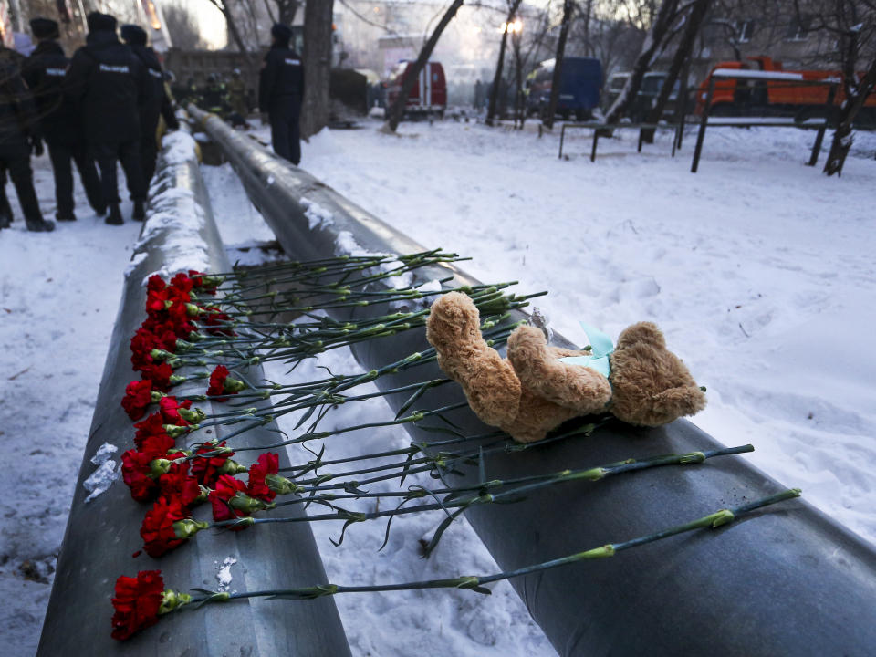 A toy and flowers lie at the scene of a collapsed apartment building in Magnitogorsk, a city of 400,000 people, about 1,400 kilometers (870 miles) southeast of Moscow, Russia, Monday, Dec. 31, 2018. At least four people died Monday when sections of an apartment building collapsed after an apparent gas explosion in Russia's Ural Mountains region, officials said, and hundreds of rescuers are searching for survivors under the debris. (AP Photo/Maxim Shmakov)