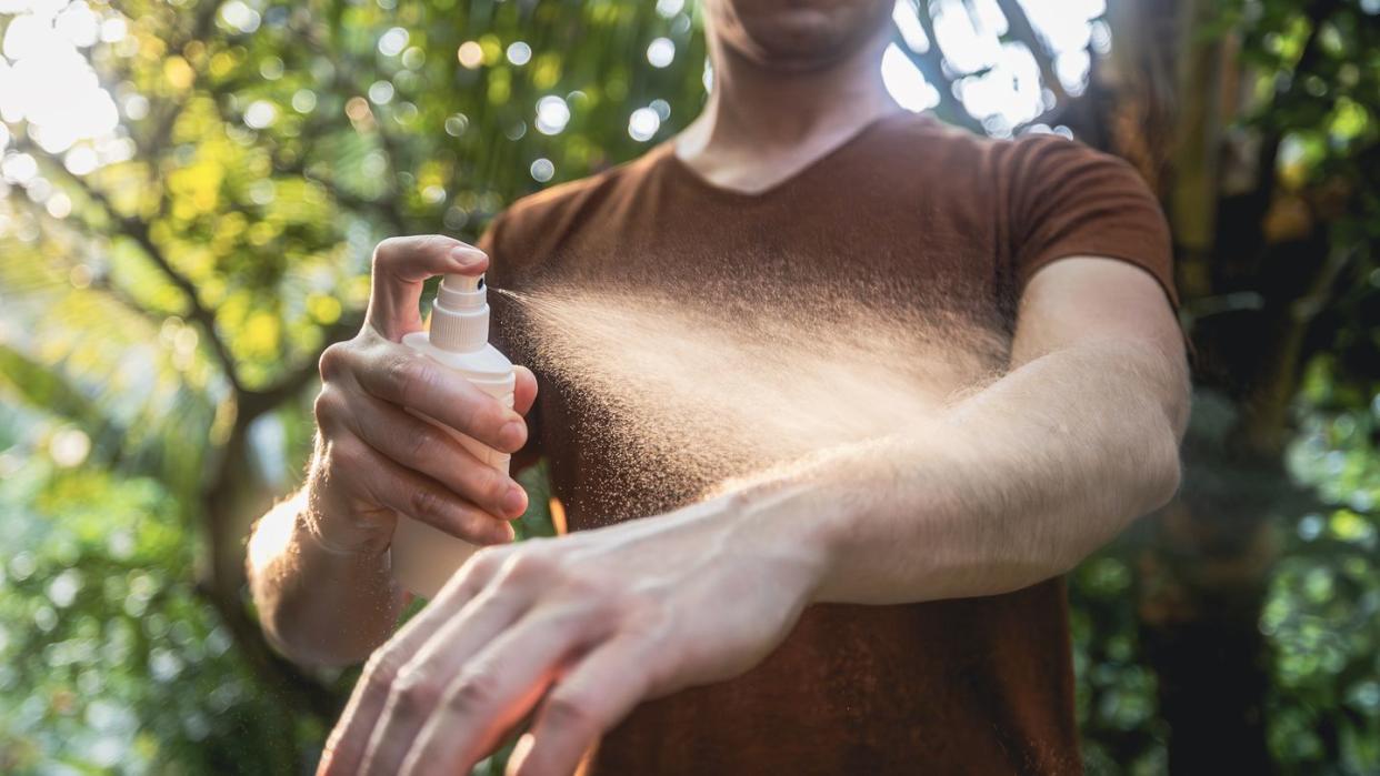 man while applying insect repellent