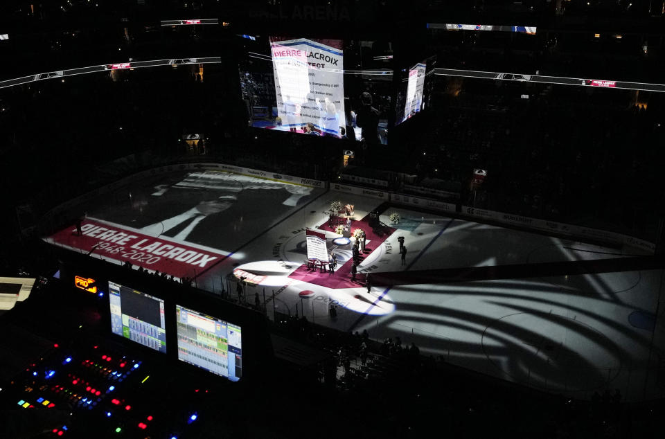 A banner is raised to honor former Colorado Avalanche general manager Pierre Lacroix, who died from complications of COVID-19 last December, before the Avalanche host the St. Louis Blues in an NHL hockey game Saturday, Oct. 16, 2021, in Denver. (AP Photo/David Zalubowski)