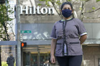 Sonia Guevara poses for a photo, Wednesday, May 18, 2022, outside the Hilton hotel where she works as a housekeeper in downtown Seattle. Many hotels across the United States have done away with daily housekeeping service, making what was already one of the toughest jobs in the hospitality industry even more grueling. (AP Photo/Ted S. Warren)