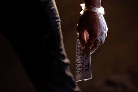 An investigator hold a tag at the site where a man was killed by unknown gunmen in Manila, Philippines early October 24, 2016. REUTERS/Damir Sagolj