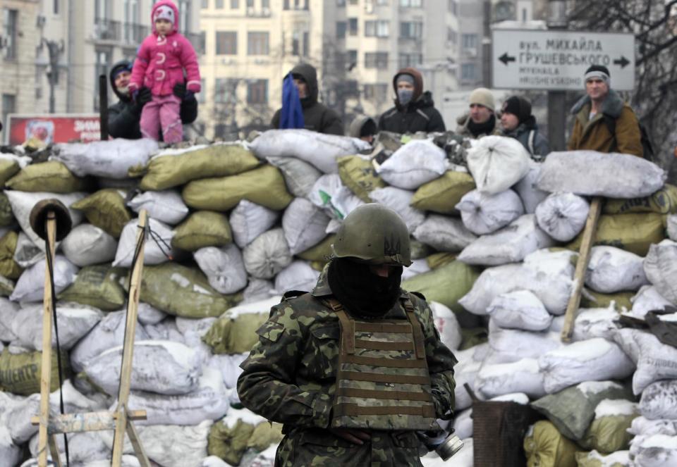 A protester guards the barricade in front of riot police in Kiev, Ukraine, Saturday, Feb. 1, 2014. Ukraine's embattled president Viktor Yanukovych is taking sick leave as the country's political crisis continues without signs of resolution. (AP Photo/Sergei Chuzavkov)