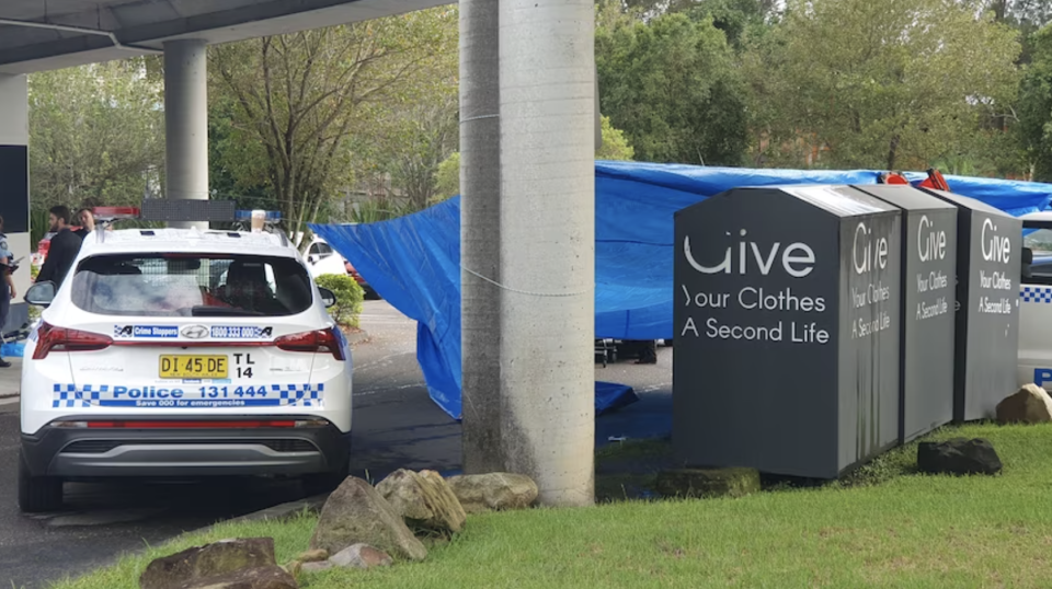 Police at the scene at Westfield Tuggerah with a tarp covering the charity bin where the man's body was found.