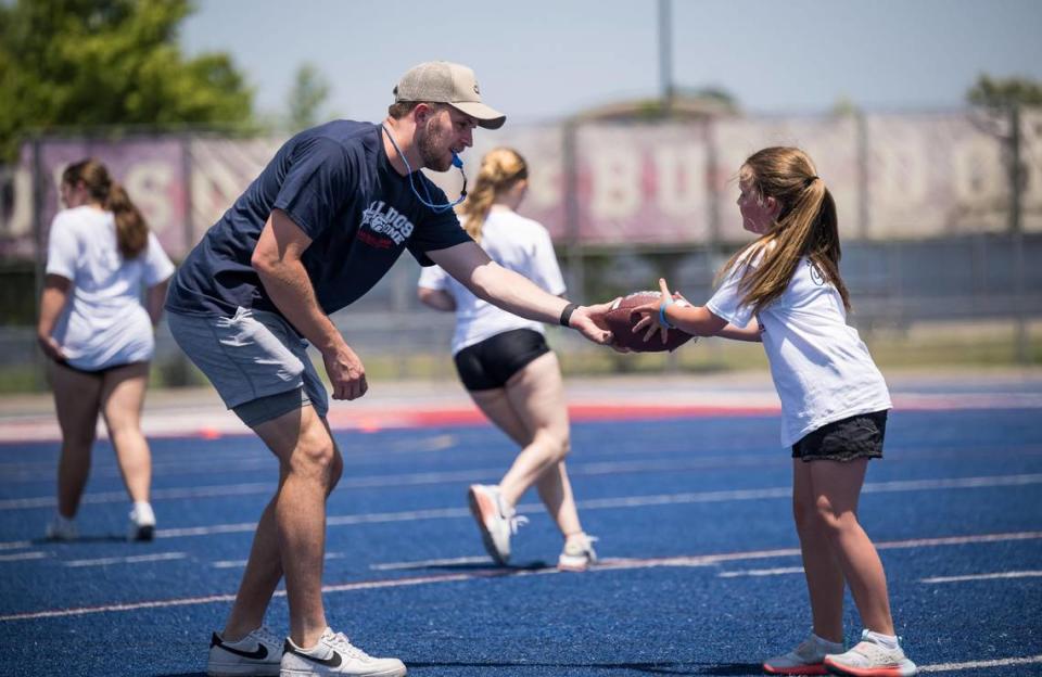 Cincinnati Bengals quarterback and former Folsom Bulldog Jacob Browning assists 10-year-old Camryn with the football during the Bulldogs Back Home 2023 football camp on Saturday, June 17, 2023, at Folsom High School. Along with Browning, current NFL players and former Bulldogs Josiah Deguara and Jonah Williams — along with former player Jordan Richards — worked alongside head coach Paul Doherty and other Folsom coaches to run the youths through drills.