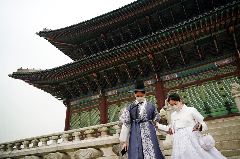 A couple in Korean traditional costumes, Hanbok, wearing masks to prevent contacting the coronavirus, walks at Gyeongbok Palace in central Seoul