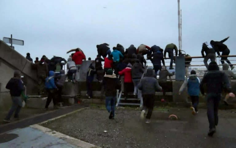 A video grab shows dozens of migrants running toward a moored ferry in the northern French port of Calais on January 23, 2016 in a bid to reach Britain before police removed them from the ship