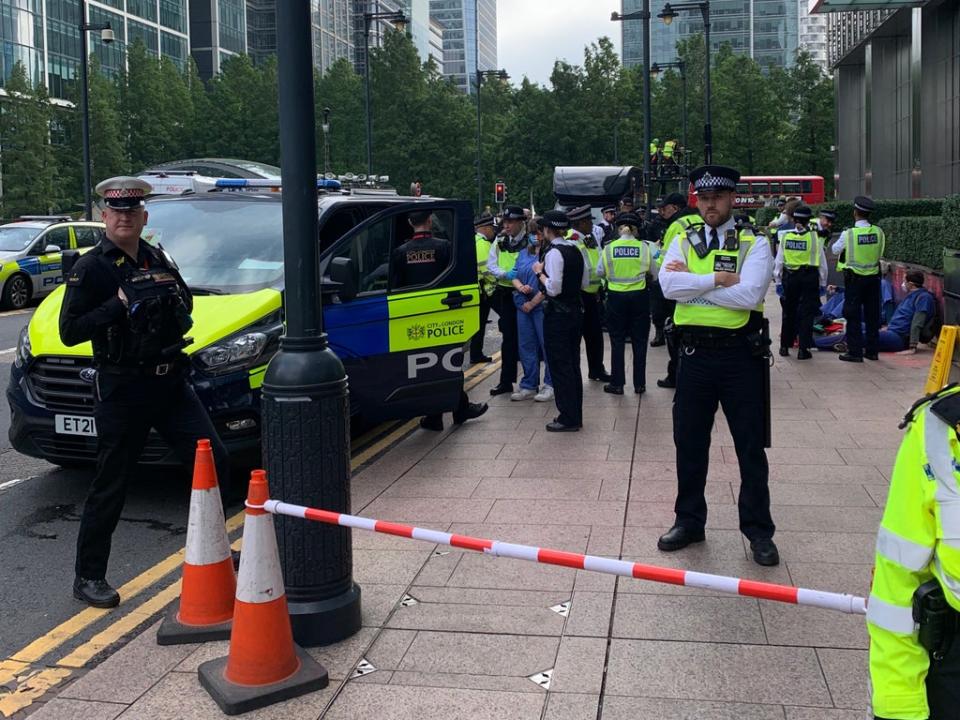 A medical student who glued herself to JP Morgan’s planter is handcuffed and loaded into a police van (The Independent)