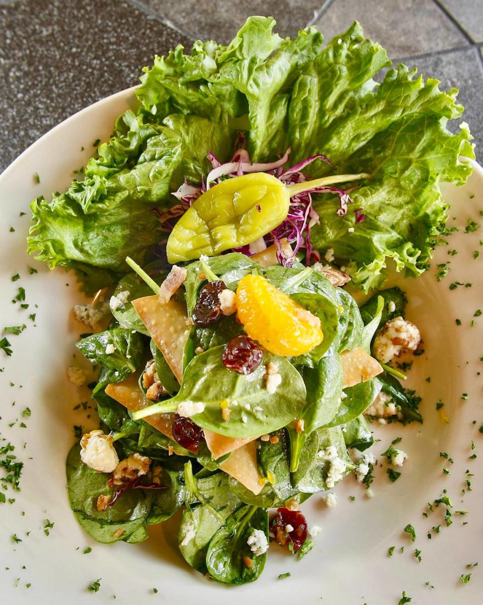 Cat City Grill’s layered spinach salad made with spinach leaves, mandarin oranges, dried cherries, pine nuts, mushrooms, bacon, and Gorgonzola crumbles, tossed in plum vinaigrette and layered between three crispy wontons.