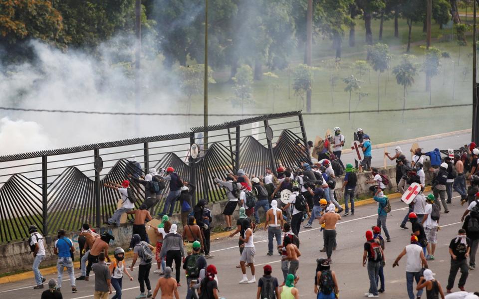 Demonstrators enter after breaking a fence surrounding an air force base during a rally against Venezuela's President Nicolas Maduro in Caracas - Credit: Reuters