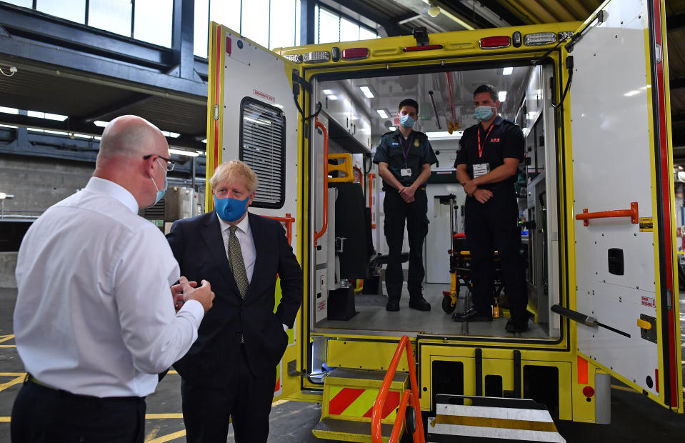 Prime Minister Boris Johnson, wearing a face mask, talks with CEO London Ambulance Service Garrett Emmerson (left), watched from inside the back of an ambulance by brothers Jack Binder (second right), a paramedic, Tom Binder (right), a firefighter, during a visit to the headquarters of the London Ambulance Service NHS Trust.