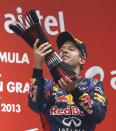 Red Bull Formula One driver Sebastian Vettel of Germany raises his trophy on the podium after winning the Indian F1 Grand Prix at the Buddh International Circuit in Greater Noida, on the outskirts of New Delhi, October 27, 2013. Vettel became Formula One's youngest four-times world champion on Sunday after winning the Indian Grand Prix for Red Bull. Red Bull also took the constructors' championship for the fourth year in a row. The victory from pole position was the 26-year-old's sixth in a row and completed a hat-trick of wins in India where no other driver has ever won since the race made its debut in 2011. REUTERS/Ahmad Masood (INDIA - Tags: SPORT MOTORSPORT F1 TPX IMAGES OF THE DAY)