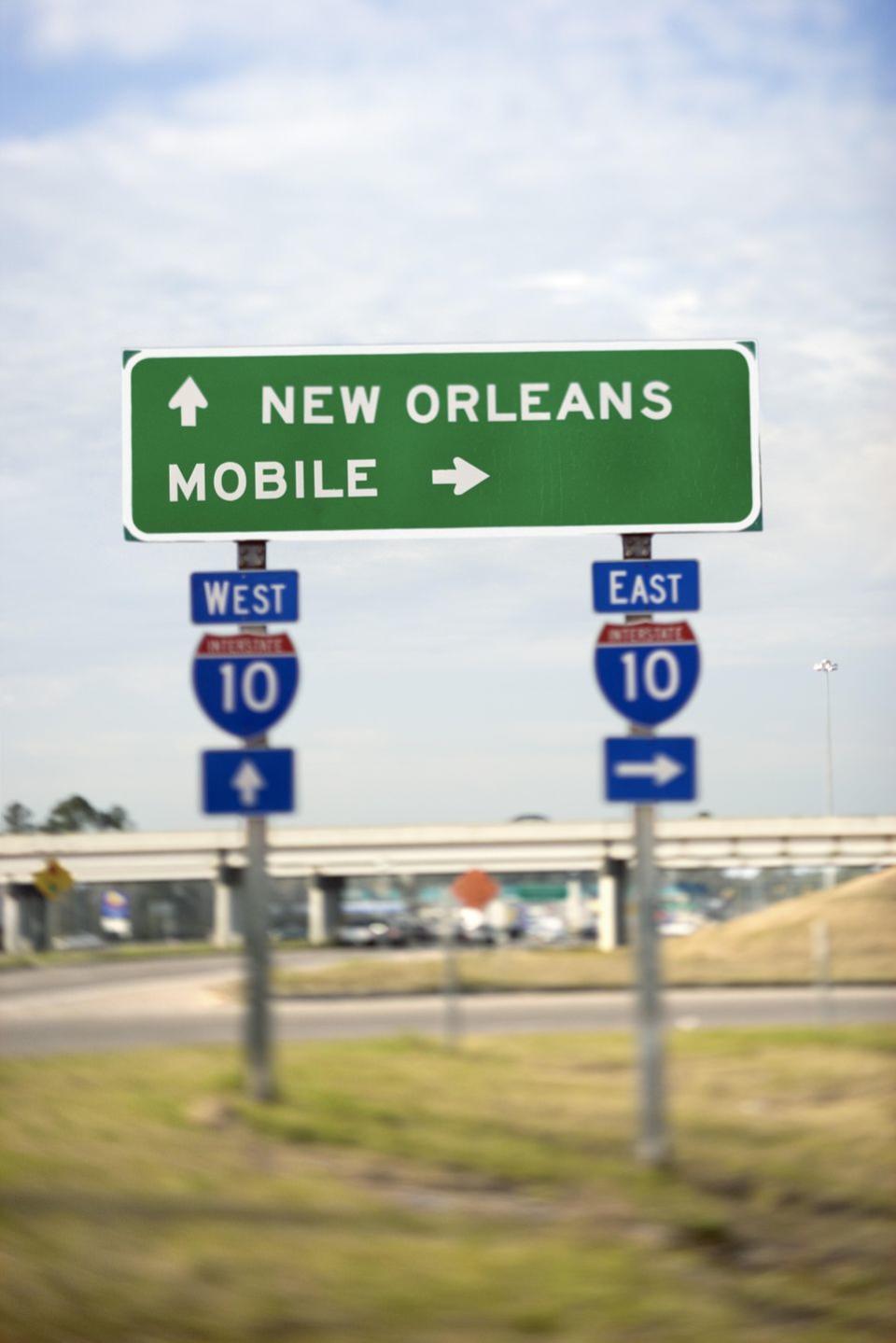 interstate 10 sign for mobile and new orleans, cities that both claim to have held the first mardi gras in the united states