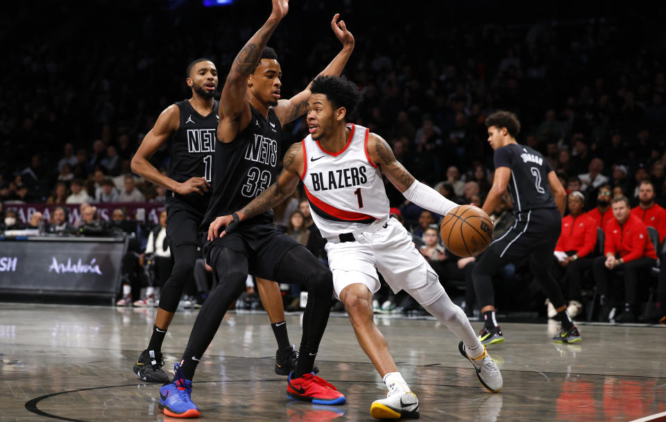 Portland Trail Blazers guard Anfernee Simons, front right, drives the baseline against Brooklyn Nets center Nic Claxton (33) and forward Mikal Bridges, left, during the first half of an NBA basketball game, Sunday, Jan 7, 2024, in New York. (AP Photo/Noah K. Murray)