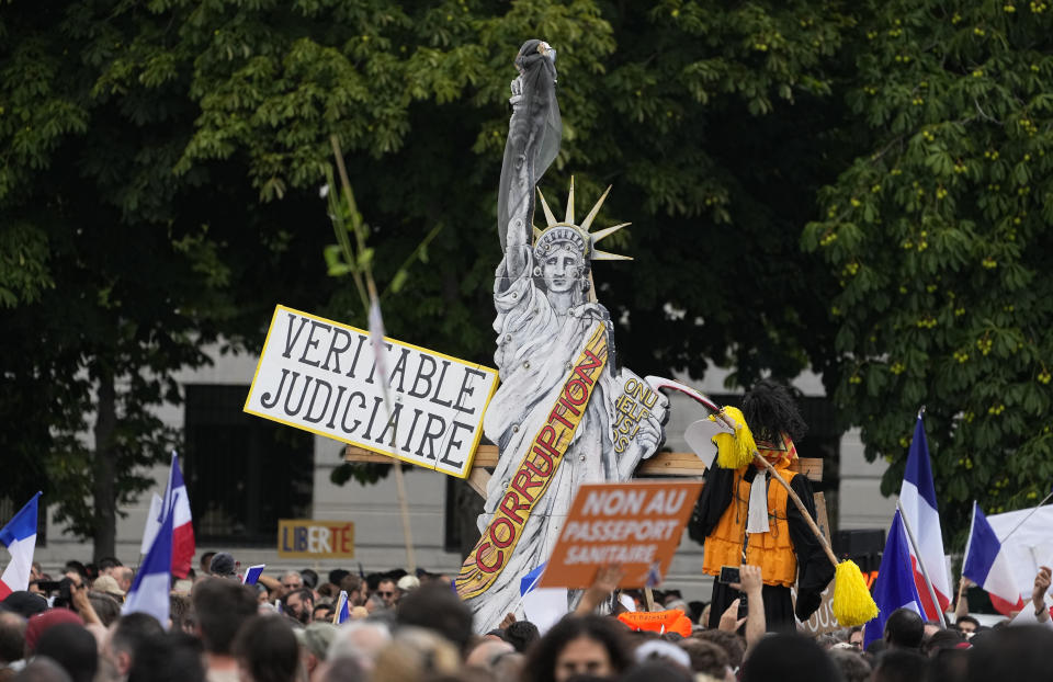 Protestors wave French flags and hold signs in front of a cardboard cutout of the Statue of Liberty during a demonstration in Paris, France, Saturday, July 31, 2021. Demonstrators gathered in several cities in France on Saturday to protest against the COVID-19 pass, which grants vaccinated individuals greater ease of access to venues. Sign reads in French "True Judiciary". (AP Photo/Michel Euler)