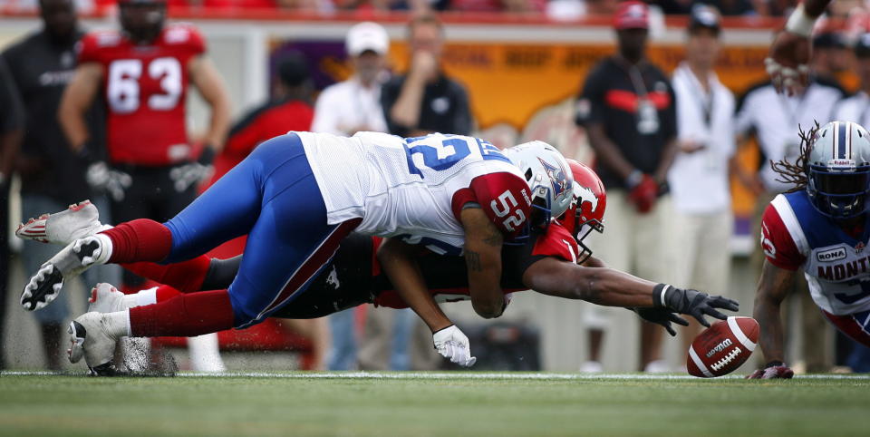 Montreal Alouettes' Marques Murrell, top, tackles Calgary Stampeders' Nik Lewis as he dives for a fumbled ball during fourth quarter CFL football action in Calgary, Alta., Sunday, July 1, 2012. THE CANADIAN PRESS/Jeff McIntosh