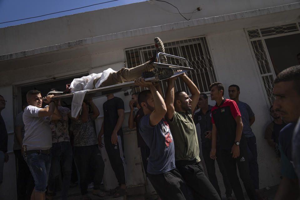 Palestinians carry the body of a man killed during fighting with Israeli forces, in Gaza City, Saturday, Oct. 7, 2023. The militant Hamas rulers of the Gaza Strip carried out an unprecedented, multi-front attack on Israel at daybreak Saturday, firing thousands of rockets as dozens of Hamas fighters infiltrated the heavily fortified border in several locations by air, land, and sea and catching the country off-guard on a major holiday. (AP Photo/Fatima Shbair)